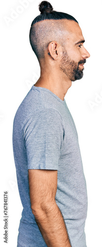 Hispanic man with ponytail wearing casual grey t shirt looking to side, relax profile pose with natural face with confident smile.