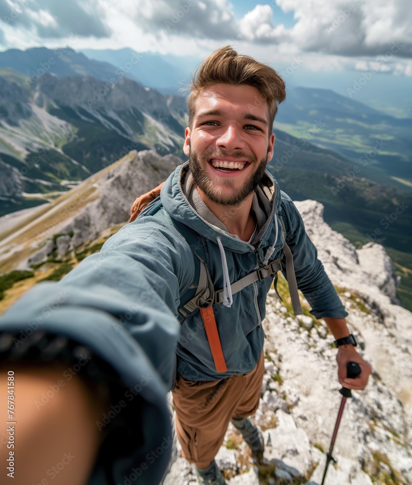 A young male hiker with a smile on his face climbing up a mountain in the midst of a mountainous landscape.