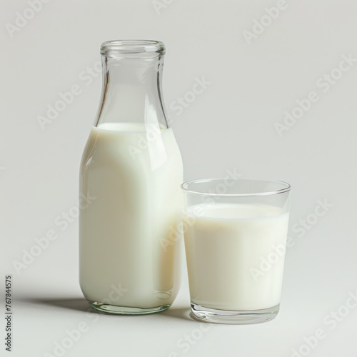 Milk in a bottle with a glass cup next to it on a light background.