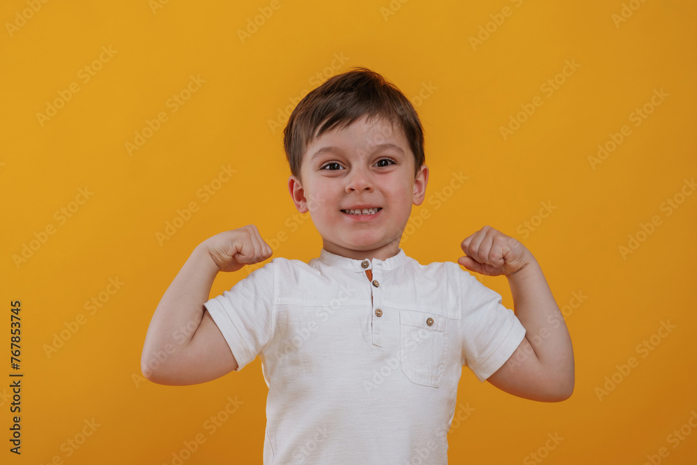 Front view. Little boy is in the studio against yellow background Front view. Little boy is in the studio against yellow background