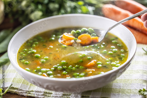 Healthy vegetable soup from fresh spring vegetables. A close-up view of a spoon full of hot soup