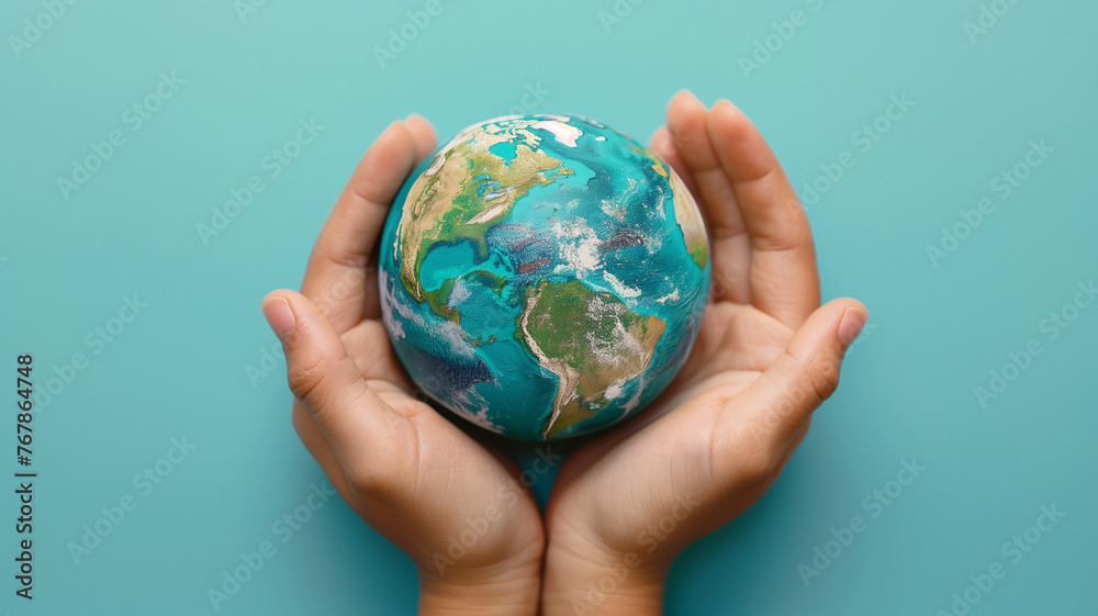 Pair of hands holding a Earth globe on blue background. World Earth Day. Earth Hour, Nature Day,