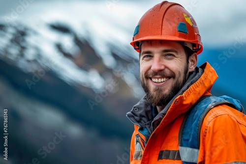 Portrait of a male worker at mountain drilling site. A young confident smiling employee in uniform with personal protective equipment (PPE) and helmet standing near the oil or gas rig platform. photo