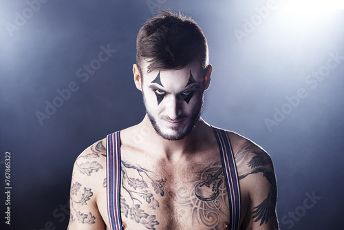 Man, mime and topless for theatre performance with dark background with light for stage, creativity and entertainment. Portrait, circus or magician performer and face paint with tattoo for show photo