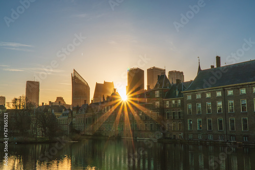 Sun rays piercing through the Binnenhof Castle, Mauritshuis museum and the modern skyline of The Hague, the Netherland. Clear sky, spring.