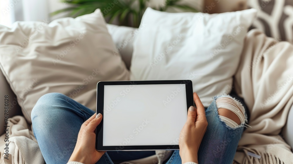 Seated person on a couch using a tablet with a blank screen. Seated person on a couch using a tablet with a blank screen.