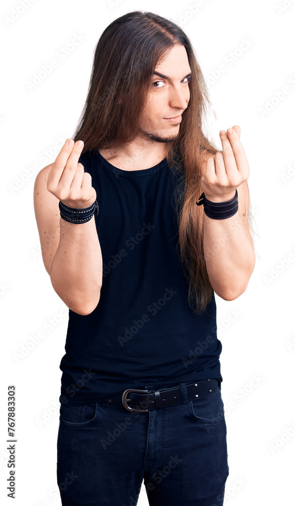Young adult man with long hair wearing goth style with black clothes doing money gesture with hands, asking for salary payment, millionaire business Young adult man with long hair wearing goth style with black clothes doing money gesture with hands, asking for salary payment, millionaire business