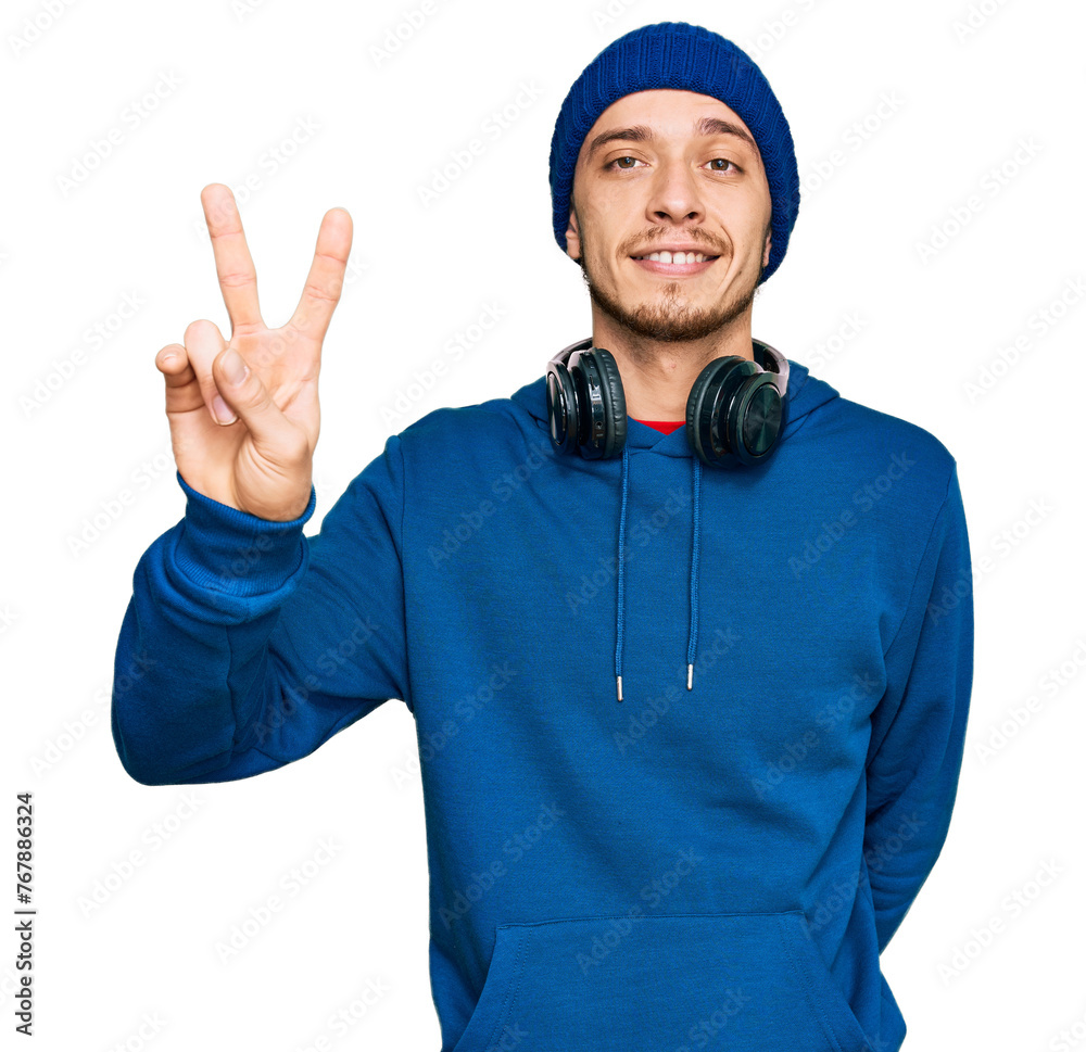 Hispanic young man wearing sweatshirt and wool hat smiling with happy face winking at the camera doing victory sign. number two. Hispanic young man wearing sweatshirt and wool hat smiling with happy face winking at the camera doing victory sign. number two.