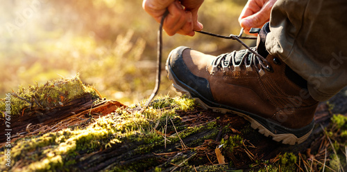 Obraz na plátně man tying hiking boot shoelace on fallen tree trunk in forest