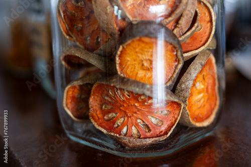 Selective focus dried bael fruit in a clear glass jar. Dried bael fruit, a Thai herb that nourishes the body. photo