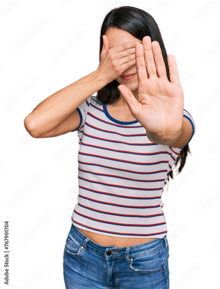 Young hispanic girl wearing casual striped t shirt covering eyes with hands and doing stop gesture with sad and fear expression. embarrassed and negative concept. Young hispanic girl wearing casual striped t shirt covering eyes with hands and doing stop gesture with sad and fear expression. embarrassed and negative concept.