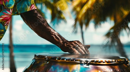 A close-up of a singer's hands playing a steel drum, with a blurred background of a tropical beach photo