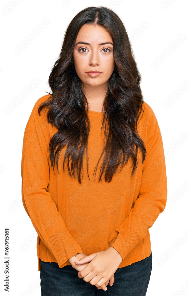 Beautiful brunette young woman wearing casual orange sweater with serious expression on face. simple and natural looking at the camera. Beautiful brunette young woman wearing casual orange sweater with serious expression on face. simple and natural looking at the camera.