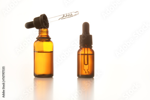 Two brown vials with black dropper caps isolated on white.