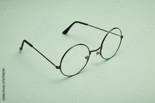 Open metal rimmed spectacles isolated on light-green.