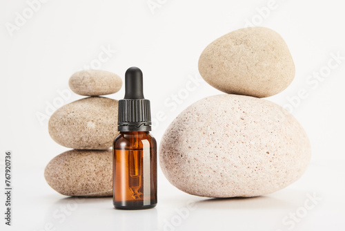Glass brown bottle is in front of spa stones pyramids.