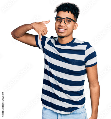 Young african american man wearing casual clothes and glasses smiling doing phone gesture with hand and fingers like talking on the telephone. communicating concepts.