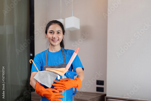 Cleaning product, and basket with woman asian staff cleaning service in bedroom to clean bacteria at apartment. cleaner or maid with container to work in room