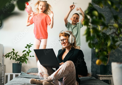 Remote work at home: A girl in a jacket and pajamas, a call worker contacts a client via video conference. Children run around, make loud noises and get in the way.