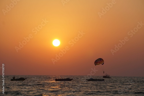 there is a man parasailing on the water with a sun setting in the