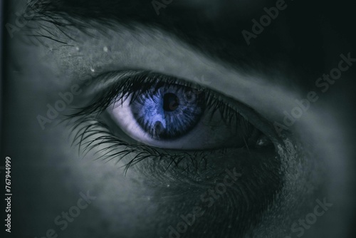 Close-up of a blue eye illuminated in a darkened setting