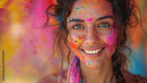 Happy Indian woman in traditional Indian dress with colorful powder on her face smiling and celebrating the holi festival