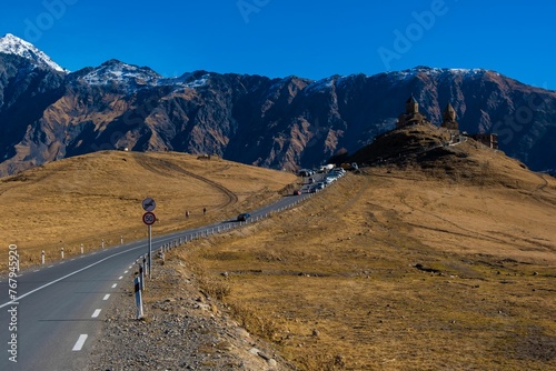 Winding road leading up a mountain toward a castle in Kazbegi, Georgia