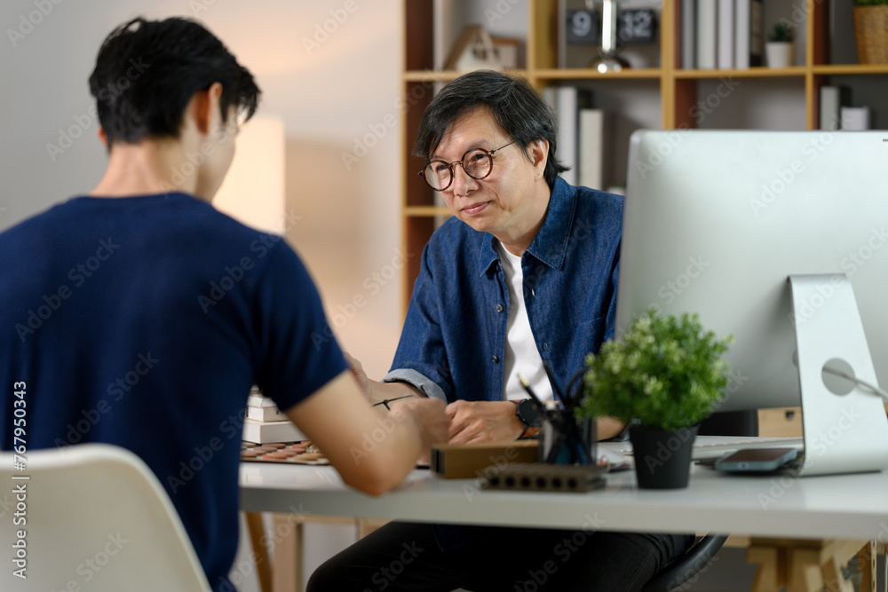 Obraz premium Middle age male interior designer discussing home renovation project with his client in office