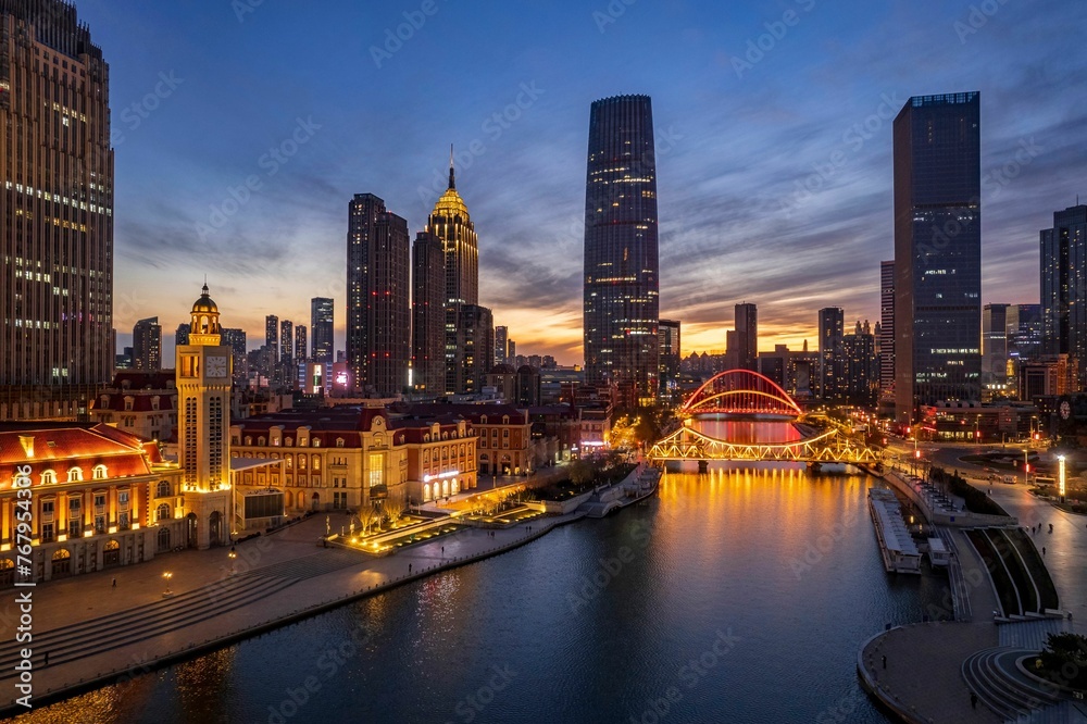 Aerial shot of an urban skyline with landmarks along the Haihe River in Tianjin, China at sunset