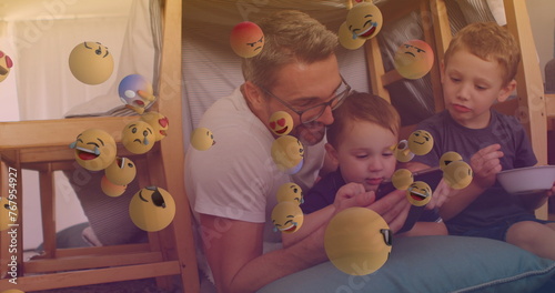 Image of falling emoji over happy caucasian family spending time together