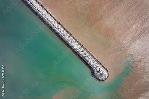 Aerial shot of the lond white stony pier on the sea on a sunny day photo