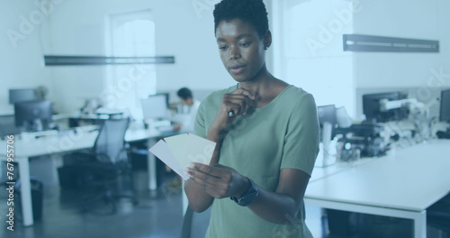 Image of world map and icons over african american woman working in office