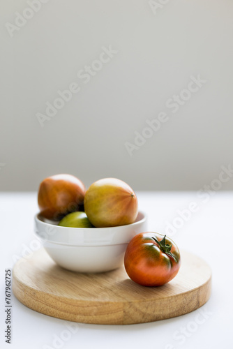 Fototapeta Naklejka Na Ścianę i Meble -  Fresh daejeo tomato in a white bowl under warm sunlight indoor natural light on white background