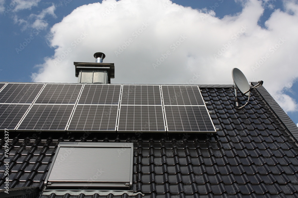 Obraz premium Photovoltaikanlage auf einem Dach in Lippetal Büninghausen mit blauem Himmel und Wolken.