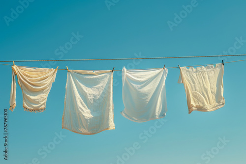 White clothes and linen hanging on a washing line against a clear blue sky