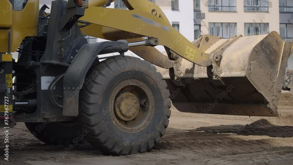 A construction site is being cleared by a yellow bulldozer with strong tires, moving dirt and debris. The vehicles wheels are covered in mud and tread marks are visible on the asphalt A construction site is being cleared by a yellow bulldozer with strong tires, moving dirt and debris. The vehicles wheels are covered in mud and tread marks are visible on the asphalt