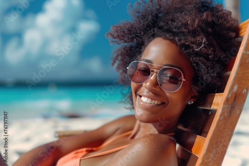 Portrait of happy young black woman relaxing on wooden deck chair at tropical beach 