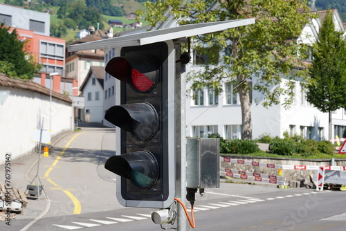 Portable traffic light powered by solar panels situated on the road to guide traffic during construction work in Schwyz, Switzerland. photo