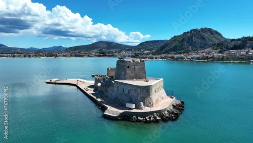 Aerial drone cinematic video of castle of Bourtzi built at sea a popular attraction in city of Nafplio as seen in the morning with nice white clouds and deep blue sky, Argolida, Greece photo