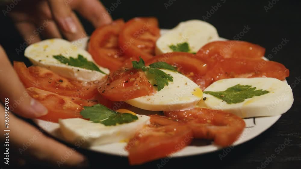 Waiter's hands put a plate of Italian caprese salad on the table. Waiter's hands put a plate of Italian caprese salad on the table.