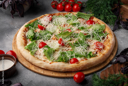 A classic caesar pizza on a grey table.