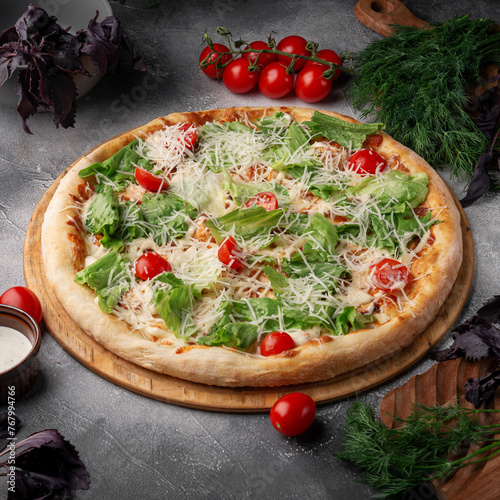 A classic caesar pizza on a grey table.