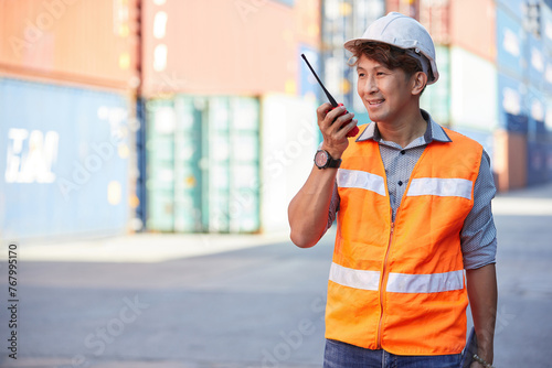 factory worker or engineer using walkie talkie and talking about work in containers warehouse storage