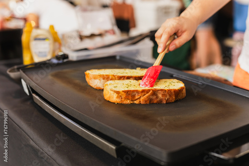 Woman cooking garlic bread with and herbs on iron pan.