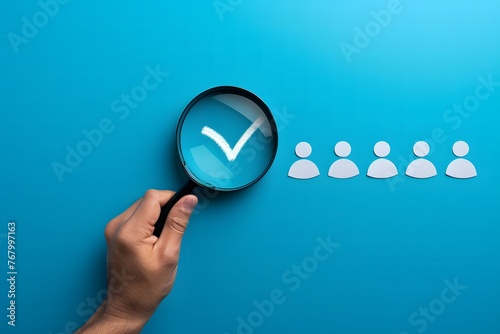 Finding the Right People for Jobs, Hand holding magnifying glass with check mark and people icon on blue background photo