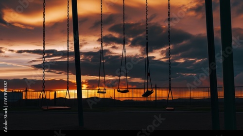 Silhouetted playground swings against a dramatic twilight sky, suggesting quiet moments or the passage of time.