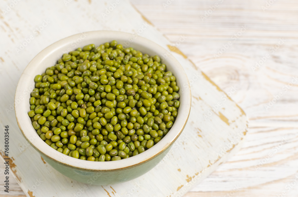 Green mung beans in a ceramic bowl on a white wooden background. Organic legumes. Vegan and vegetarian food. The concept of healthy eating. Horizontal orientation. Copy space. Selective focus. Green mung beans in a ceramic bowl on a white wooden background. Organic legumes. Vegan and vegetarian food. The concept of healthy eating. Horizontal orientation. Copy space. Selective focus.