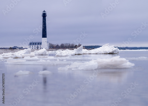 Spring comes, the sea ice melts. In the background is a lighthouse in Sõrve - landmark of Saaremaa in Estonia. The sea is calm and light blue.