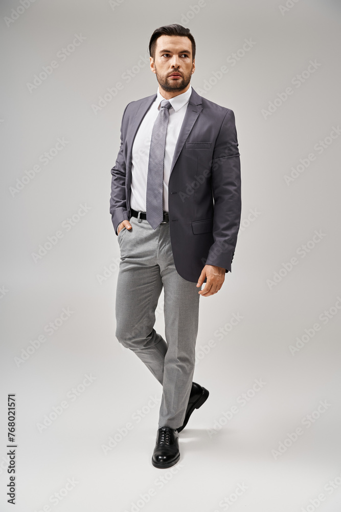 handsome businessman with bristle posing with hand in pocket of pants on grey background handsome businessman with bristle posing with hand in pocket of pants on grey background