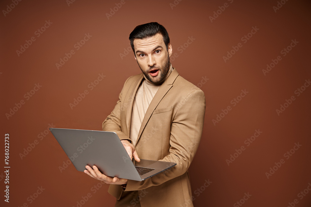 shocked and handsome professional using his laptop while working remotely on beige background